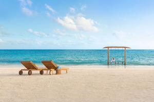 uma praia com duas cadeiras e um pavilhão na praia em Hilton Maldives Amingiri Resort & Spa em Malé