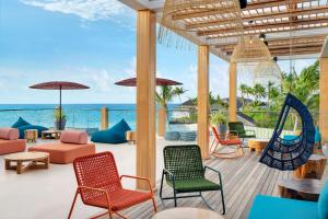 eine Terrasse mit Stühlen, einer Schaukel und dem Meer in der Unterkunft Hilton Maldives Amingiri Resort & Spa in Male City