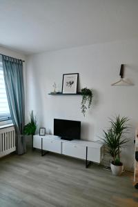 un soggiorno con TV a schermo piatto su una parete bianca di Modernes Apt mit direkter Anbindung zur City und Messe ad Hannover