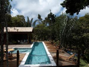 a pool at a resort with a house and trees at Refúgio Integração in Mata de Sao Joao