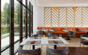 a dining room with tables and chairs and windows at DoubleTree by Hilton Shymkent in Shymkent