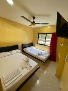 1 dormitorio con 2 camas y TV de pantalla plana en HOTEL LA CANCHITA, en Puerto Triunfo