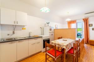 クラヴィツァにあるApartments with parking space Krvavica, Makarska - 6749のテーブルと椅子のあるキッチンと白いキャビネットのあるキッチン +16枚の写真