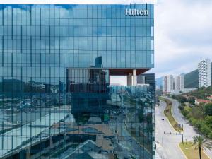 un grand bâtiment en verre avec un panneau hilton dans l'établissement Hilton Monterrey, à Monterrey