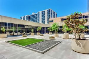 a building with a courtyard with trees in front of it at Hilton Los Angeles Airport in Los Angeles