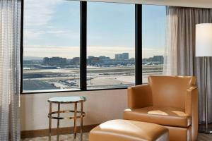 a waiting room at an airport with a chair and a window at Hilton Los Angeles Airport in Los Angeles