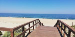 a wooden boardwalk leading to a beach with people on it at A Villa Fortuna in Santo André