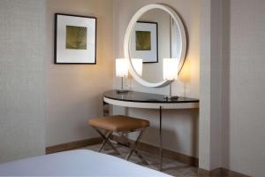 a bedroom with a mirror and a stool and a bed at Hilton Los Angeles Airport in Los Angeles