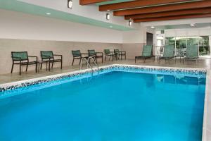 Home2 Suites by Hilton Lexington University / Medical Center في ليكسينغتون: مسبح مع كراسي وطاولات في فندق