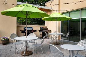 two tables and chairs with green umbrellas on a patio at Home2 Suites by Hilton Lexington University / Medical Center in Lexington