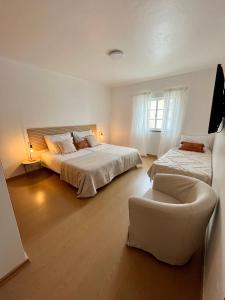 a white bedroom with two beds and a chair at A Villa Fortuna in Santo André