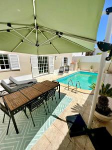 un patio con una mesa y una sombrilla verde en A Villa Fortuna, en Santo André