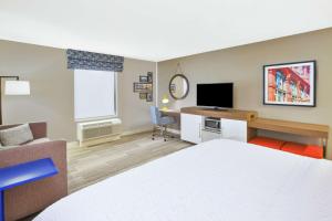 Cette chambre comprend un lit et un bureau avec une télévision. dans l'établissement Hampton Inn & Suites Oakwood Village-Cleveland, à Oakwood