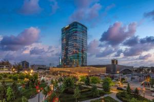 Hilton Tashkent City في طشقند: مبنى طويل في مدينة عند الغسق