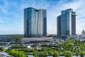 deux grands bâtiments dans une ville avec un parc dans l'établissement Hilton Tashkent City, à Tachkent