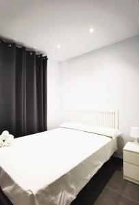 - un lit blanc dans une chambre avec un rideau noir dans l'établissement El Comienzo, à Tolède