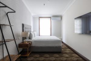 Southern Cross Hotel في سيدني: غرفة نوم بيضاء بها سرير ونافذة