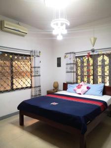 a bedroom with a large bed with blue sheets at SRL Villa in Phumi Ta Phul