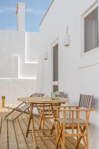 einen Holztisch und Stühle auf einer Terrasse in der Unterkunft Villa da Comporta - Quarto Praia da Comporta T0 in Comporta