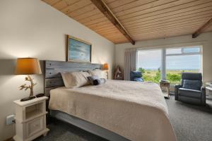 a bedroom with a bed and a chair and a window at The Tides by the Sea in Seaside