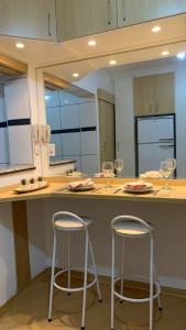 una cocina con dos taburetes en un mostrador con copas de vino en Studio completo com vaga entre o Centro e Cambuí, en Campinas
