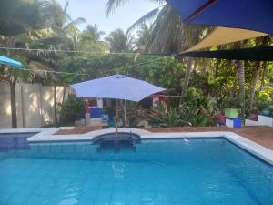 ein Regenschirm neben einem Pool mit Pool in der Unterkunft MARDEORO BEACH HOUSE in Barra de Santiago
