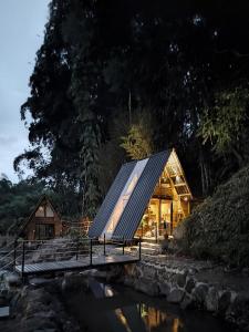 ein Glashaus mit einem Metalldach neben einem Fluss in der Unterkunft Senz Glamping - Mindo in Mindo
