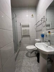 a white bathroom with a toilet and a sink at Al Arda HOTEL in Tashkent