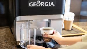 a person is holding a cup of coffee in a coffee maker at Tokyu Stay Shibuya in Tokyo