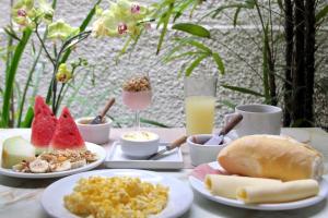 uma mesa coberta com pratos de alimentos e bebidas em Pousada e Hostel Barra da Tijuca no Rio de Janeiro