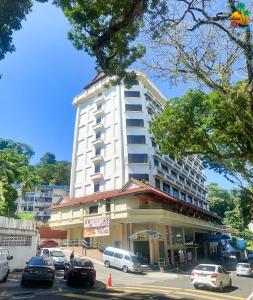 ein großes weißes Gebäude mit davor geparkt in der Unterkunft Hotel Sandakan in Sandakan