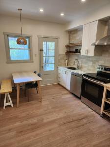 una cucina con armadi bianchi, tavolo e lavandino di Elegant two bedroom with office in Montreal a Montréal