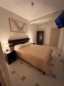 1 dormitorio con 1 cama, 2 mesas y TV en LUX - HOTEL BOUTIQUE, en Andahuaylas
