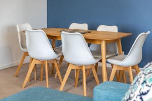 einen Holztisch mit weißen Stühlen um ihn herum in der Unterkunft Heritage 303 in Tuncurry