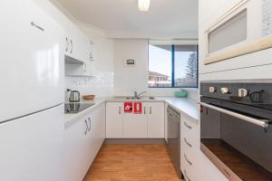 eine weiße Küche mit weißen Schränken und einem Fenster in der Unterkunft Heritage 303 in Tuncurry