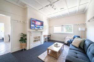 sala de estar con sofá azul y TV en Heritage Inn Bathurst, en Bathurst