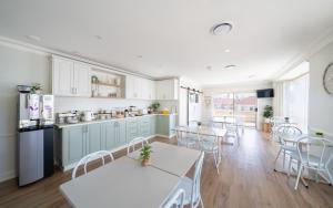 a kitchen and dining room with white tables and chairs at Heritage Inn Bathurst in Bathurst