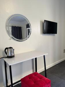 a white table with a mirror and a red stool at Elegant room in the city center in Cairo