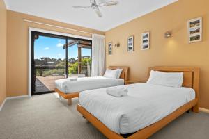 two beds in a room with a balcony at Yallingup Valley Views in Yallingup