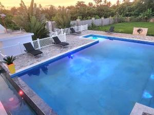 een groot blauw zwembad met stoelen in een tuin bij Roomy apartment at 5 min walk to the beach in Las Galeras