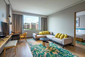 a hotel room with a couch and a bed at Hilton Garden Inn Changchun Economic Development Zone in Changchun