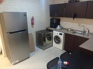 cocina con nevera y lavadora en Loft Style Partition Room in Shared Apartment in Al Barsha 1 Near MOE Metro, en Dubái