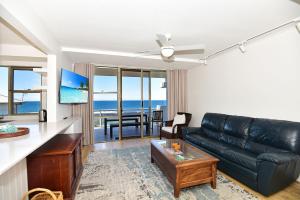 a living room with a black leather couch and a table at Beachfront on Werrina in Blue Bay 