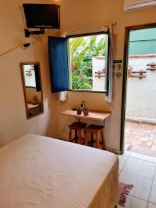 a bedroom with a bed and a table and a window at Praia Suítes Itagua Ubatuba in Ubatuba