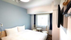1 dormitorio con cama blanca y ventana en Toyoko Inn Chigasaki Shiyakusho, en Chigasaki