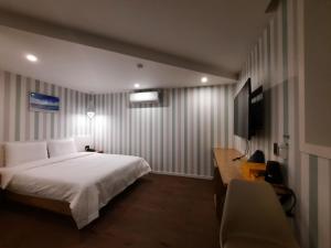 Rein Hotel Busan Yeonsan في بوسان: غرفة نوم بسرير ومكتب وتلفزيون