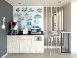 a kitchen with a counter with a microwave and a stool at Hop Inn Udonthani in Udon Thani