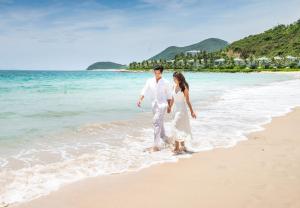 un hombre y una mujer caminando por la playa en Vinpearl Resort Nha Trang, en Nha Trang