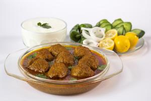 a glass bowl filled with meatballs and a bowl of dipping sauce at Collection O 794 Hotel Radha Kanhaiya in Salt Lake City