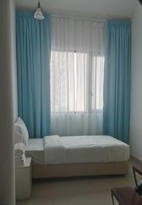 een slaapkamer met een bed met blauwe gordijnen en een raam bij YY48 Hotel 2 Mins Walk From Masjid Jamek LRT Station in Kuala Lumpur